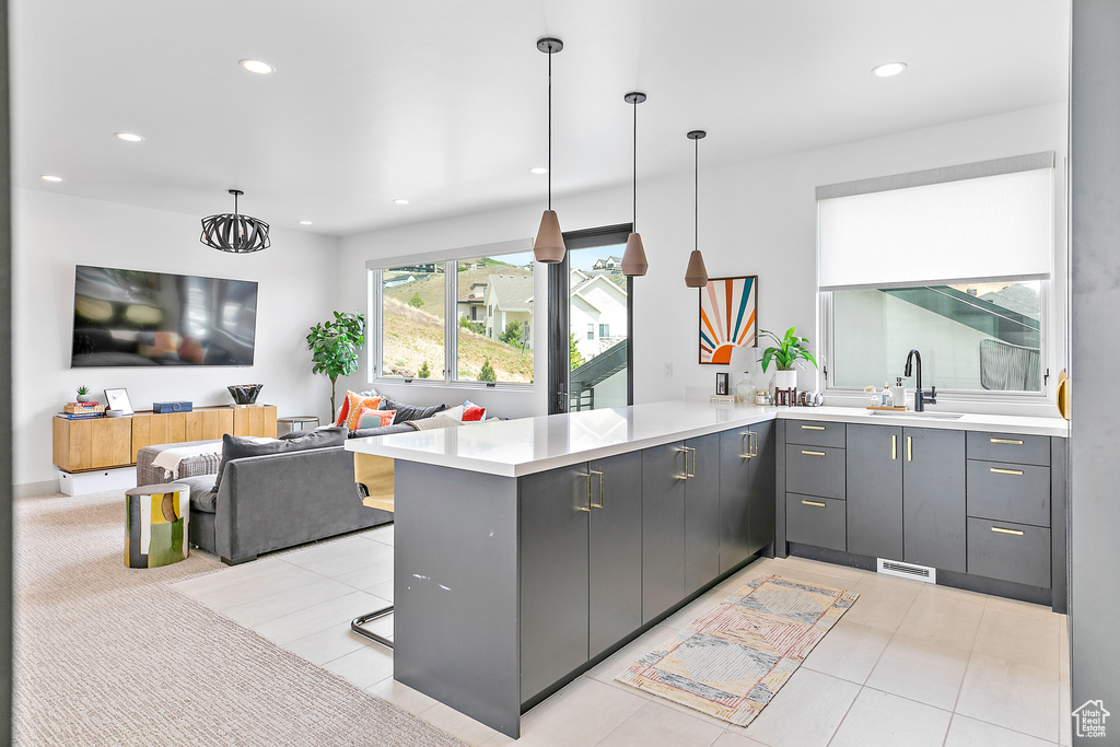 Kitchen with a sink, a peninsula, gray cabinets, recessed lighting, and light countertops