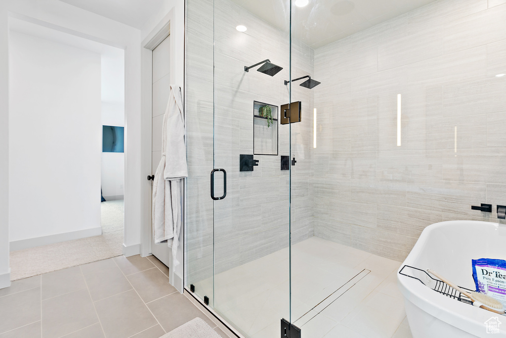Full bathroom featuring a shower stall, a freestanding bath, and tile patterned floors