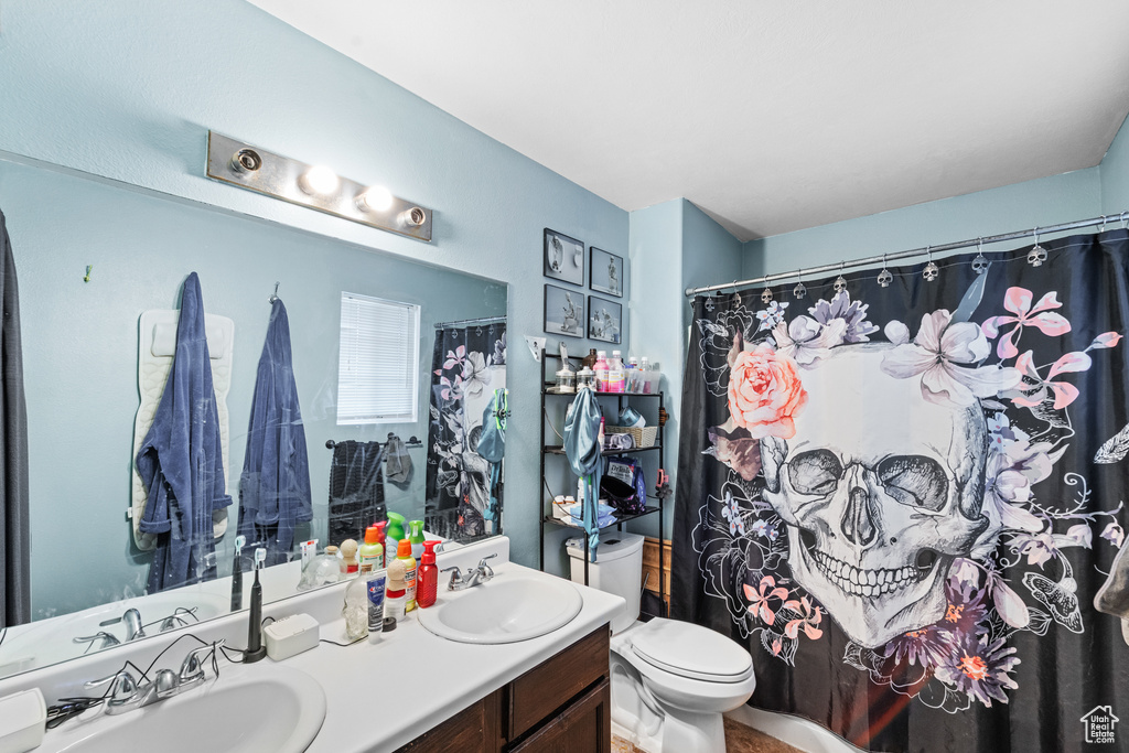 Bathroom featuring double vanity, toilet, and curtained shower