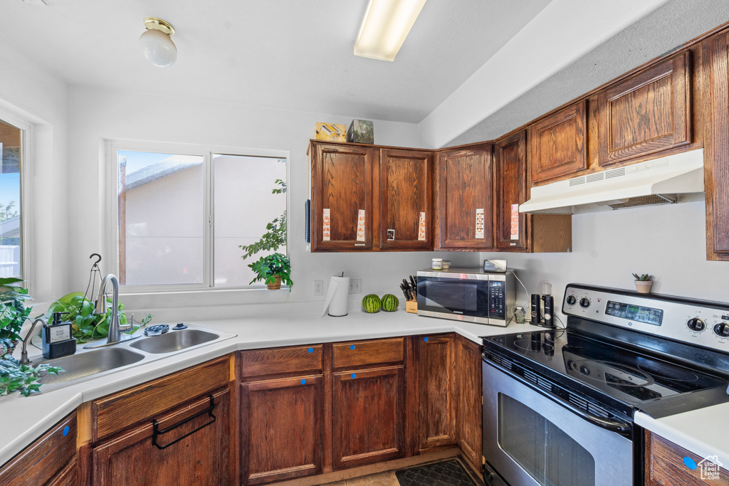 Kitchen featuring stainless steel appliances, under cabinet range hood, a sink, and healthy amount of natural light