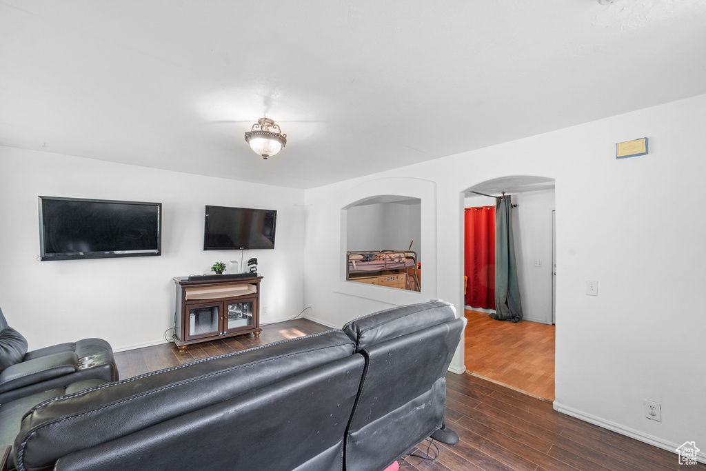 Living room featuring wood finished floors, arched walkways, and baseboards