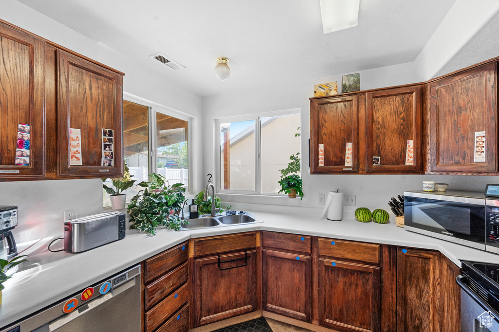 Kitchen featuring stainless steel appliances, a sink, and light countertops