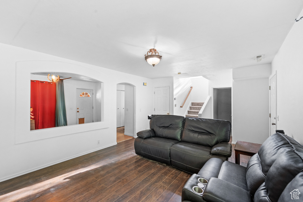 Living area with arched walkways, dark wood-style flooring, stairs, and baseboards