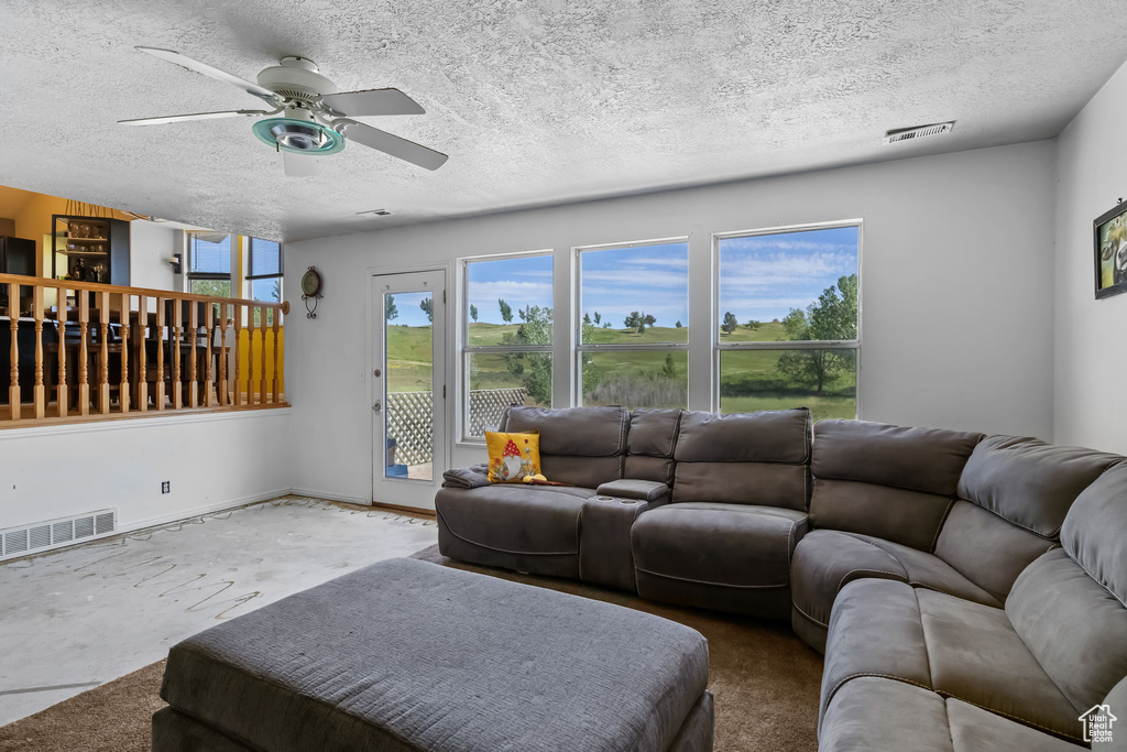 Living room featuring a ceiling fan, a textured ceiling, and baseboards