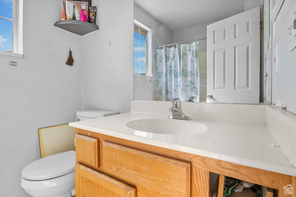 Full bathroom with toilet, vanity, and curtained shower