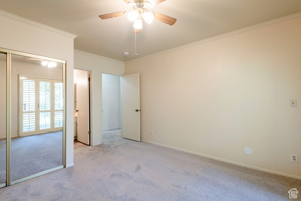 Unfurnished bedroom with carpet flooring, ornamental molding, baseboards, ceiling fan, and a closet