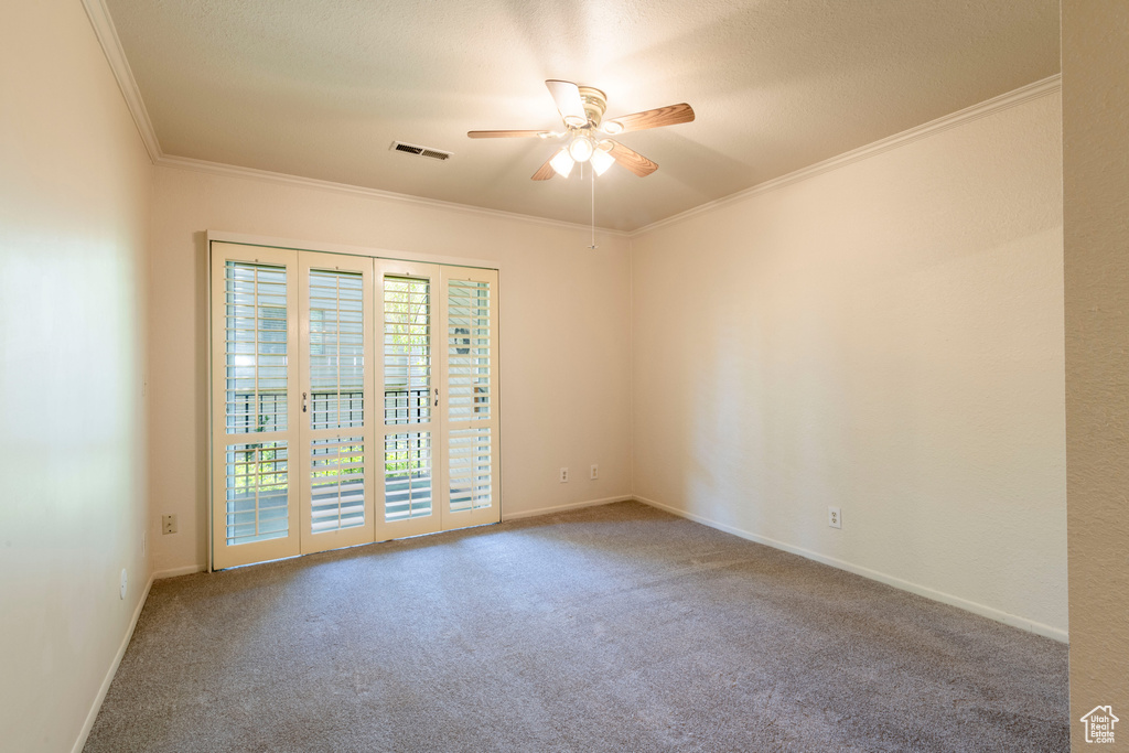 Spare room featuring ornamental molding, carpet floors, ceiling fan, and baseboards