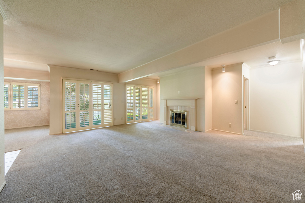 Unfurnished living room featuring carpet, a fireplace with flush hearth, and a textured ceiling
