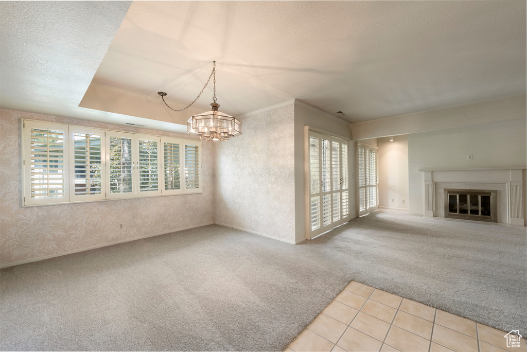 Unfurnished dining area featuring carpet flooring, plenty of natural light, a chandelier, and a glass covered fireplace