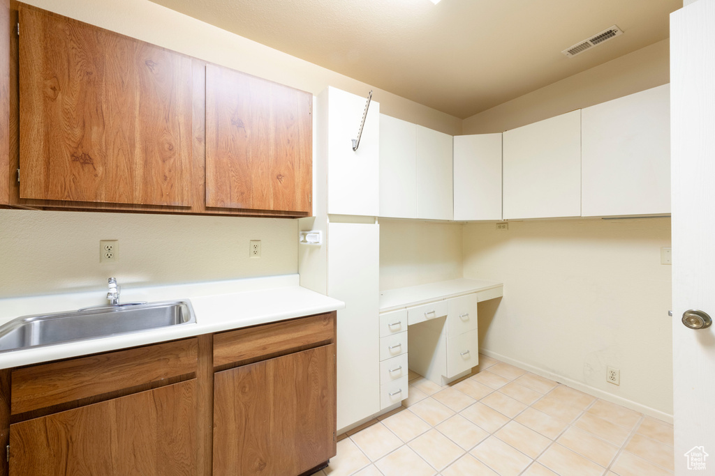 Washroom with a sink, a desk, baseboards, and light tile patterned floors