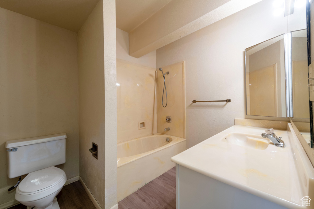 Bathroom featuring wood finished floors, toilet, vanity, and shower / bath combination