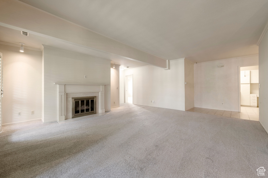 Unfurnished living room with carpet flooring, a fireplace with flush hearth, and ornamental molding