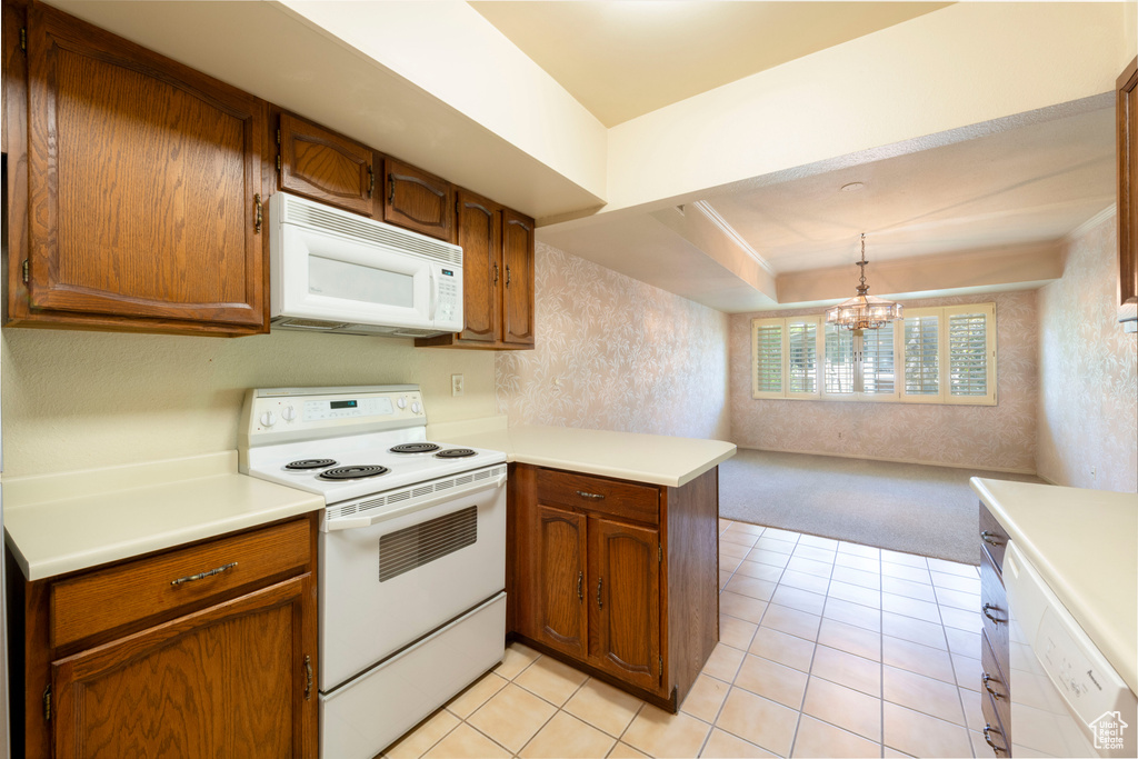 Kitchen featuring white appliances, a peninsula, light carpet, and light countertops