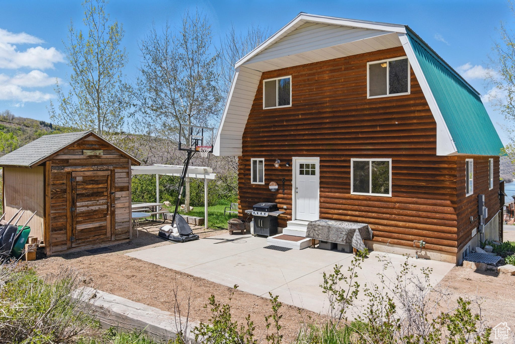 Rear view of house featuring a gambrel roof, entry steps, and a patio