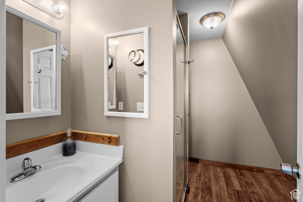 Bathroom featuring wood finished floors, vanity, and a shower with shower door