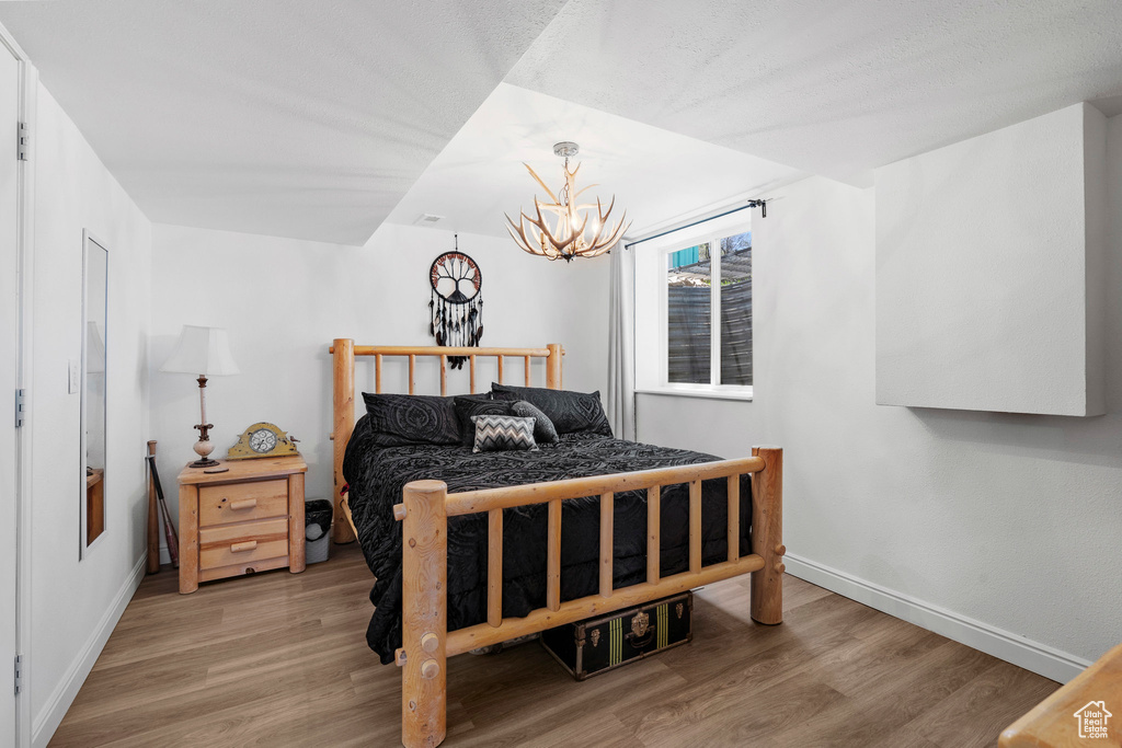 Bedroom featuring wood finished floors, a chandelier, and baseboards