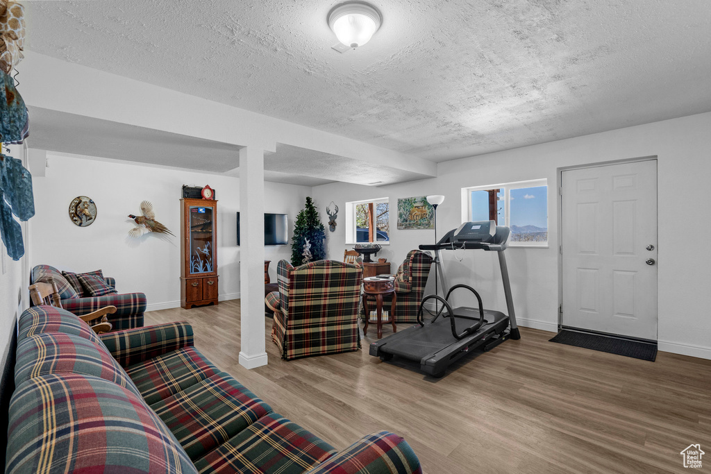 Living area featuring wood finished floors, a textured ceiling, and baseboards