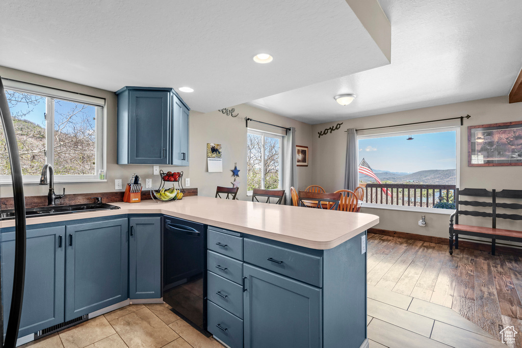 Kitchen with a peninsula, a sink, black dishwasher, blue cabinets, and recessed lighting