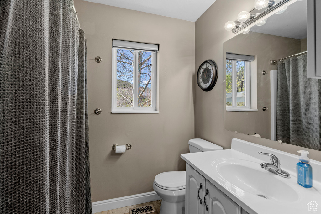 Full bath featuring toilet, vanity, baseboards, a shower with shower curtain, and tile patterned floors