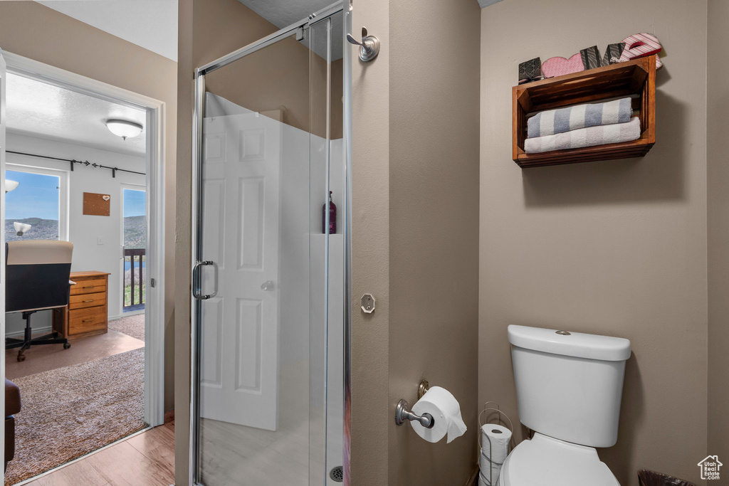 Bathroom with a shower stall, toilet, and wood finished floors