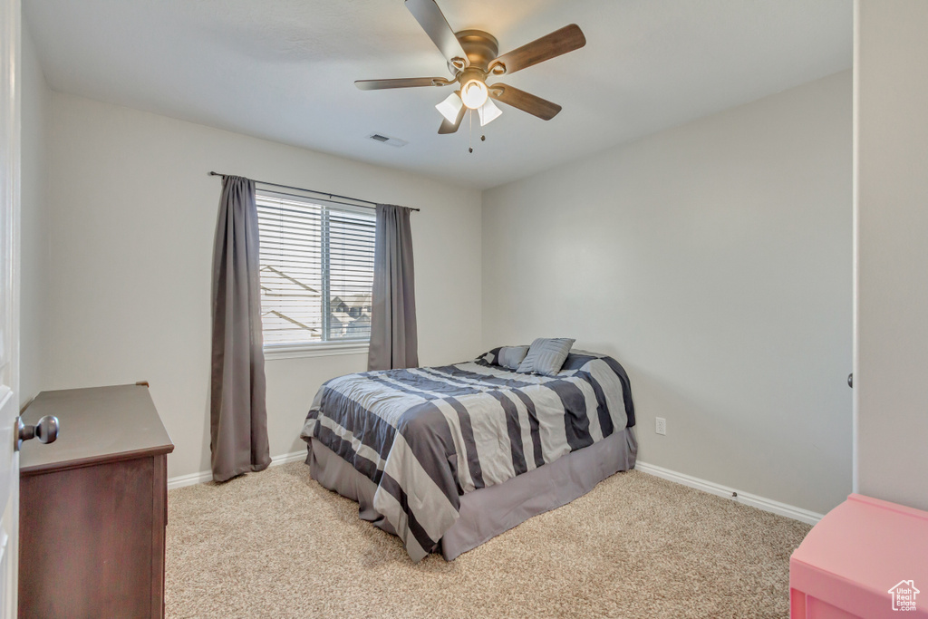 Bedroom featuring light carpet, baseboards, and a ceiling fan