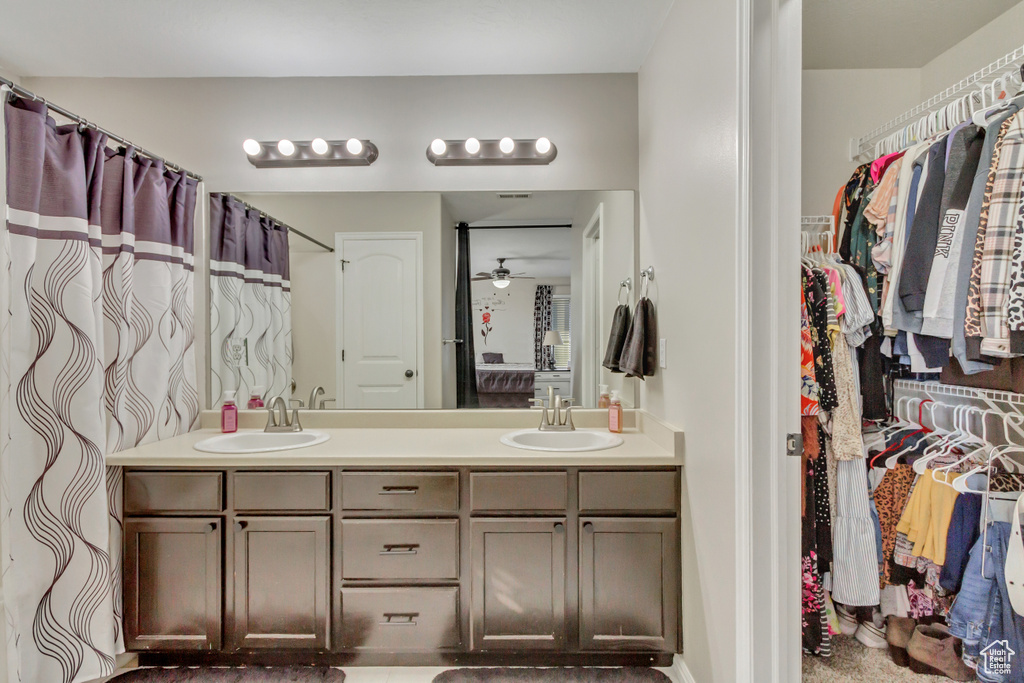 Bathroom featuring double vanity, a spacious closet, and a ceiling fan