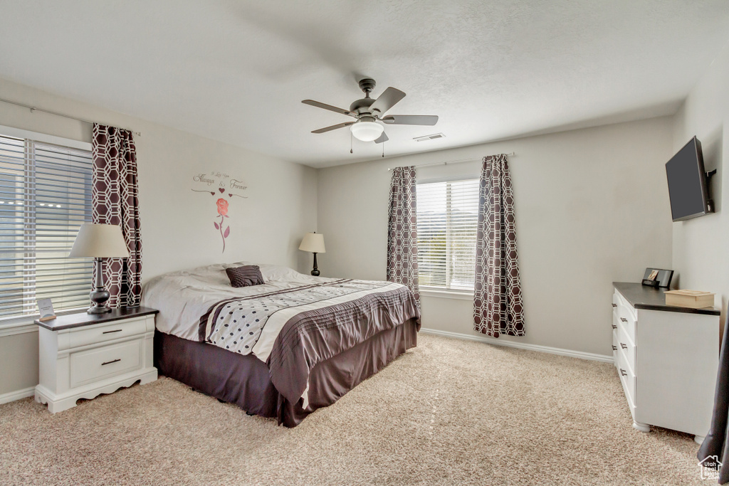 Bedroom featuring light colored carpet, baseboards, and a ceiling fan