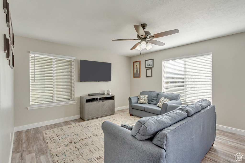Living room with a ceiling fan, baseboards, and light wood-style floors