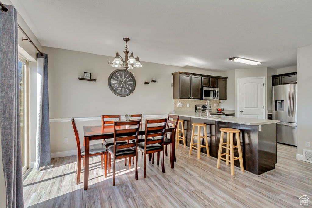 Dining space with light wood-type flooring, a chandelier, and baseboards