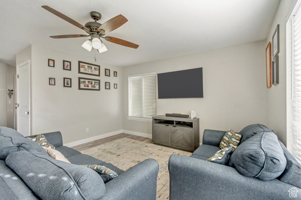 Living room with a ceiling fan, wood finished floors, and baseboards