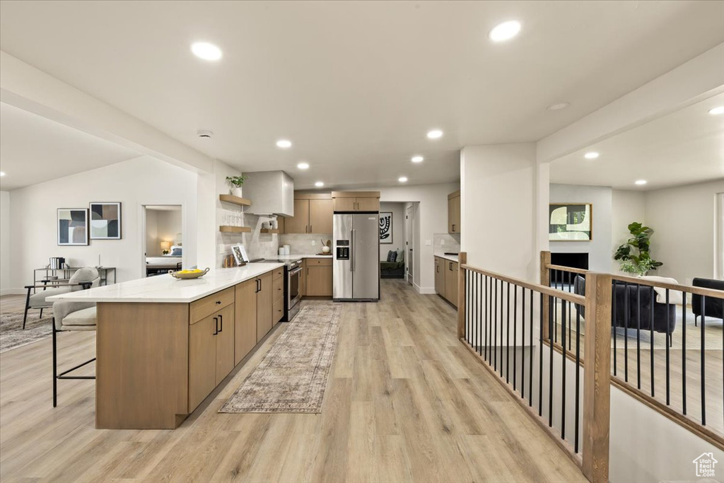 Kitchen featuring appliances with stainless steel finishes, a peninsula, light wood-type flooring, open shelves, and recessed lighting