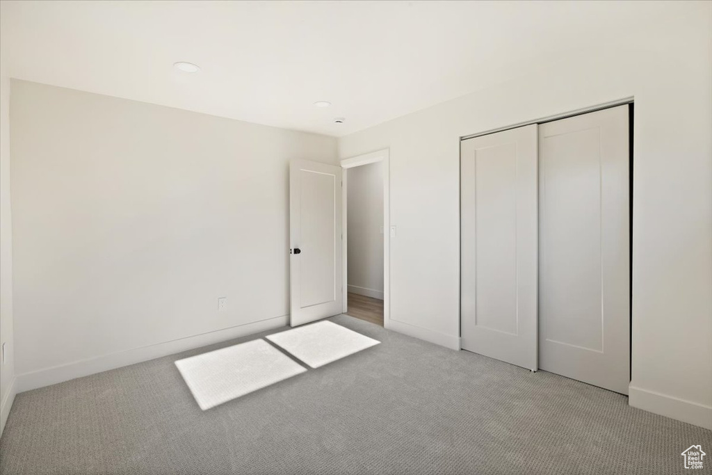 Unfurnished bedroom with light carpet, baseboards, a closet, and recessed lighting