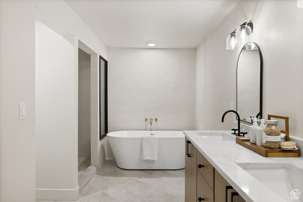 Bathroom with a soaking tub, double vanity, and marble finish floors