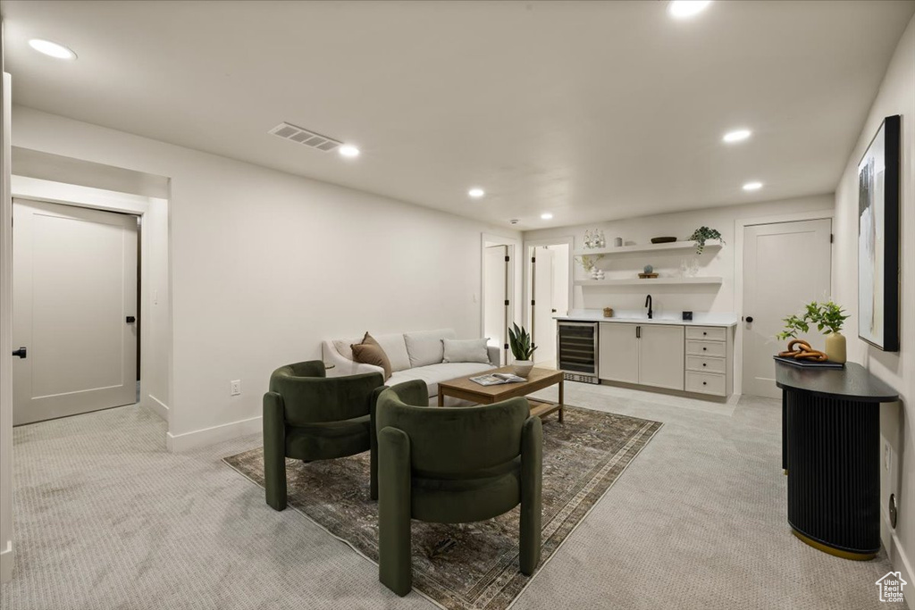 Living room with bar with sink, light colored carpet, recessed lighting, wine cooler, and baseboards