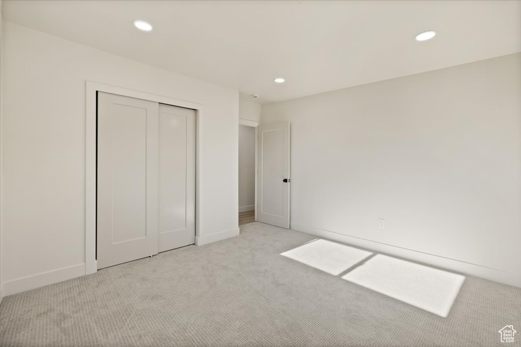 Unfurnished bedroom with light colored carpet, recessed lighting, a closet, and baseboards