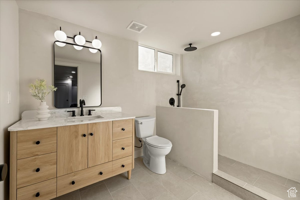 Full bath featuring vanity, a walk in shower, toilet, and tile patterned floors