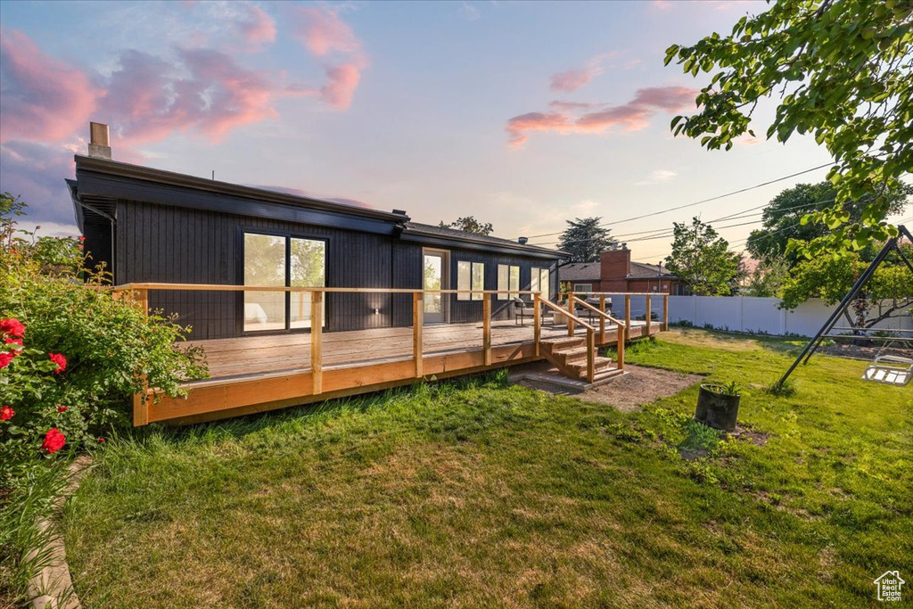 Back of house at dusk featuring a wooden deck