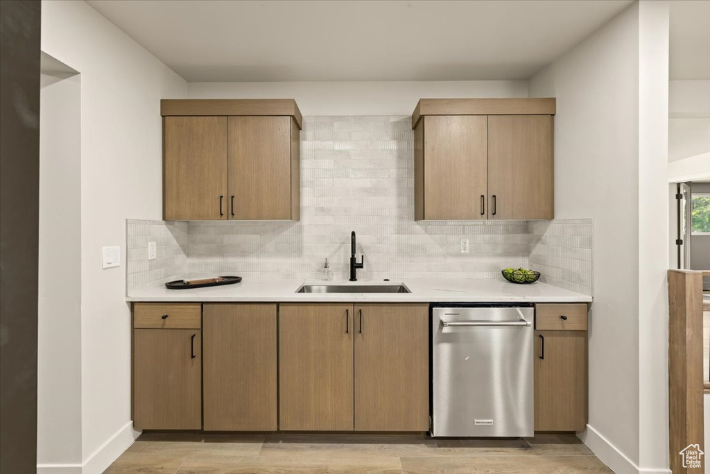 Kitchen featuring a sink, dishwasher, light countertops, and tasteful backsplash