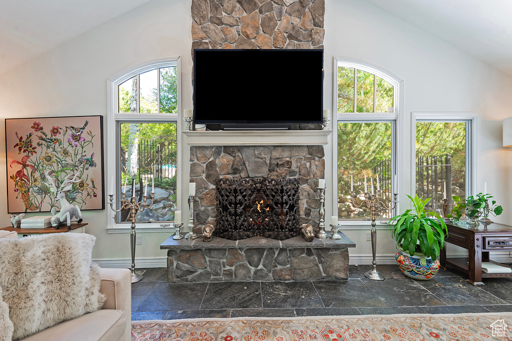 Living area featuring vaulted ceiling, baseboards, and a fireplace