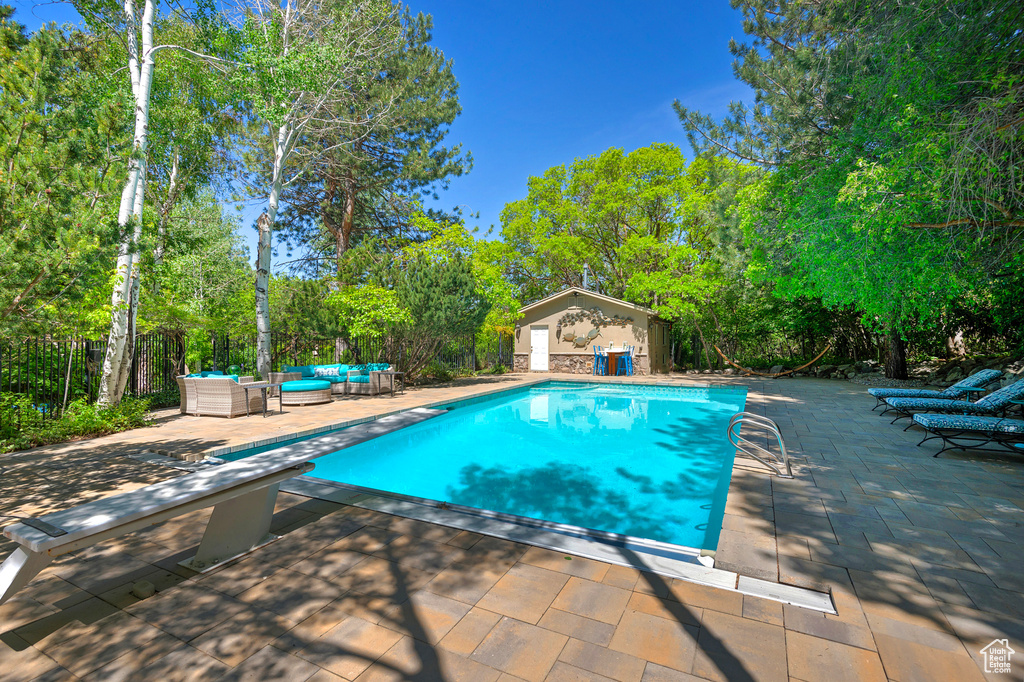 View of pool with an outdoor living space, a patio, an outbuilding, and a diving board