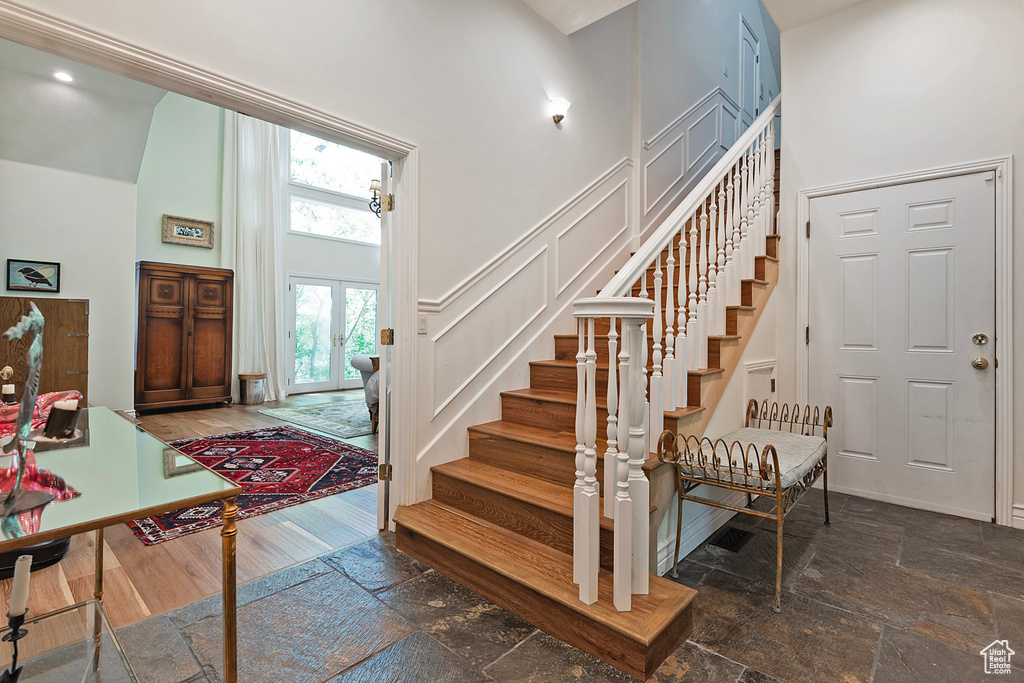 Entryway featuring a towering ceiling, stairs, stone tile floors, and a decorative wall