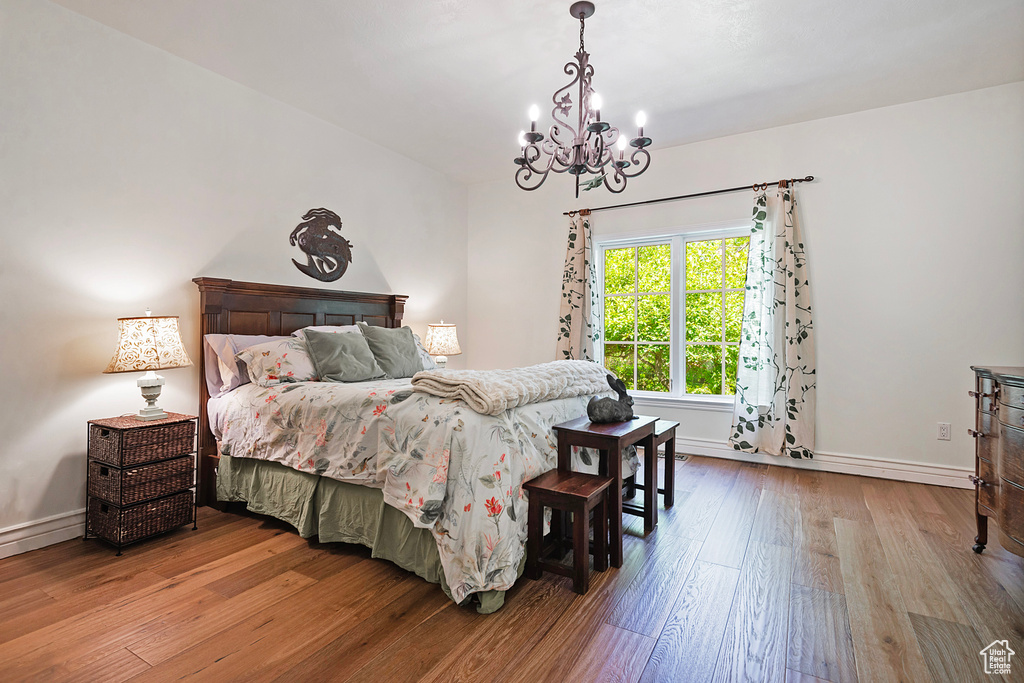 Bedroom featuring hardwood / wood-style flooring, a chandelier, and baseboards