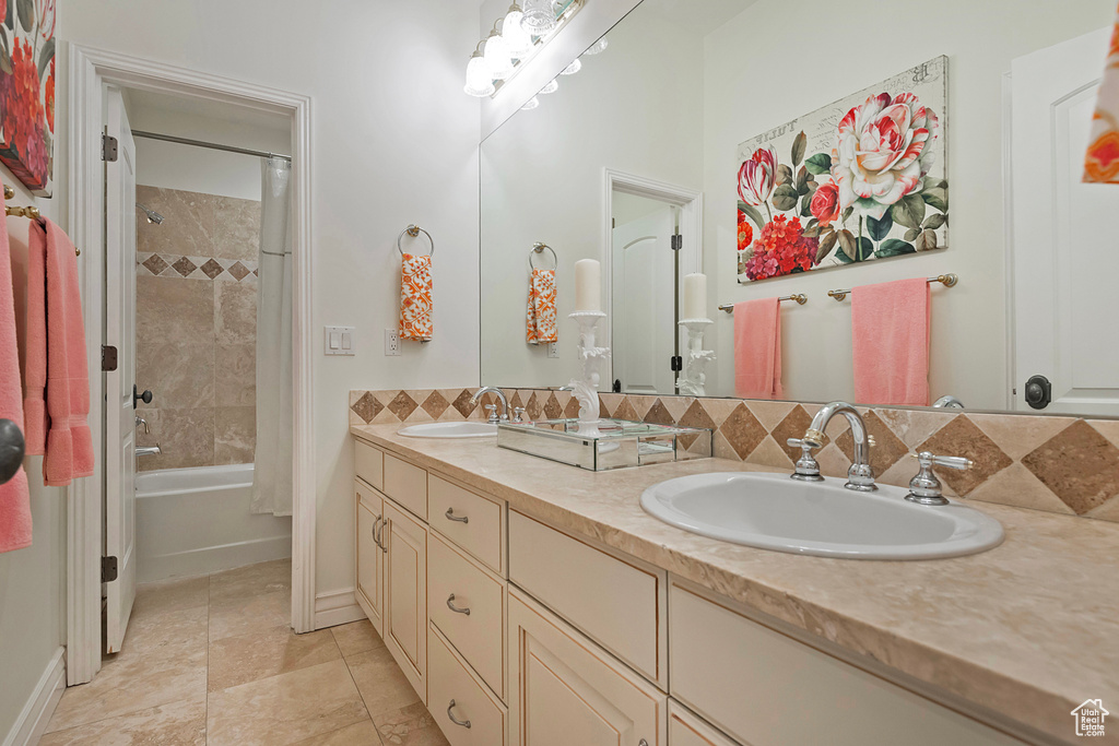 Bathroom with double vanity, shower / bath combo, tasteful backsplash, and tile patterned flooring