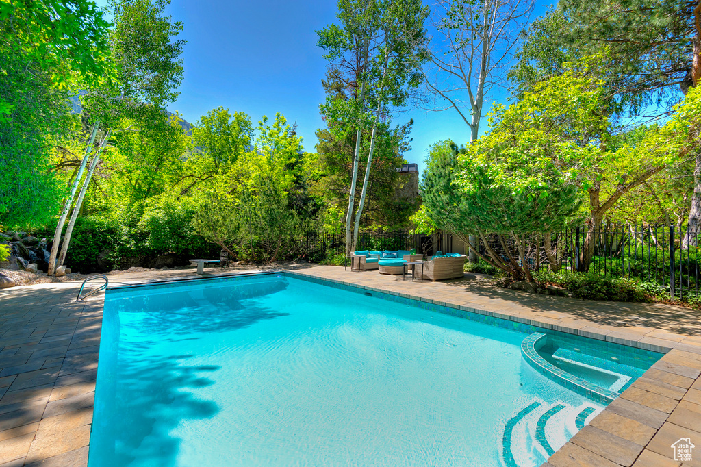 View of swimming pool with an outdoor living space, a patio area, a pool with connected hot tub, and view of wooded area