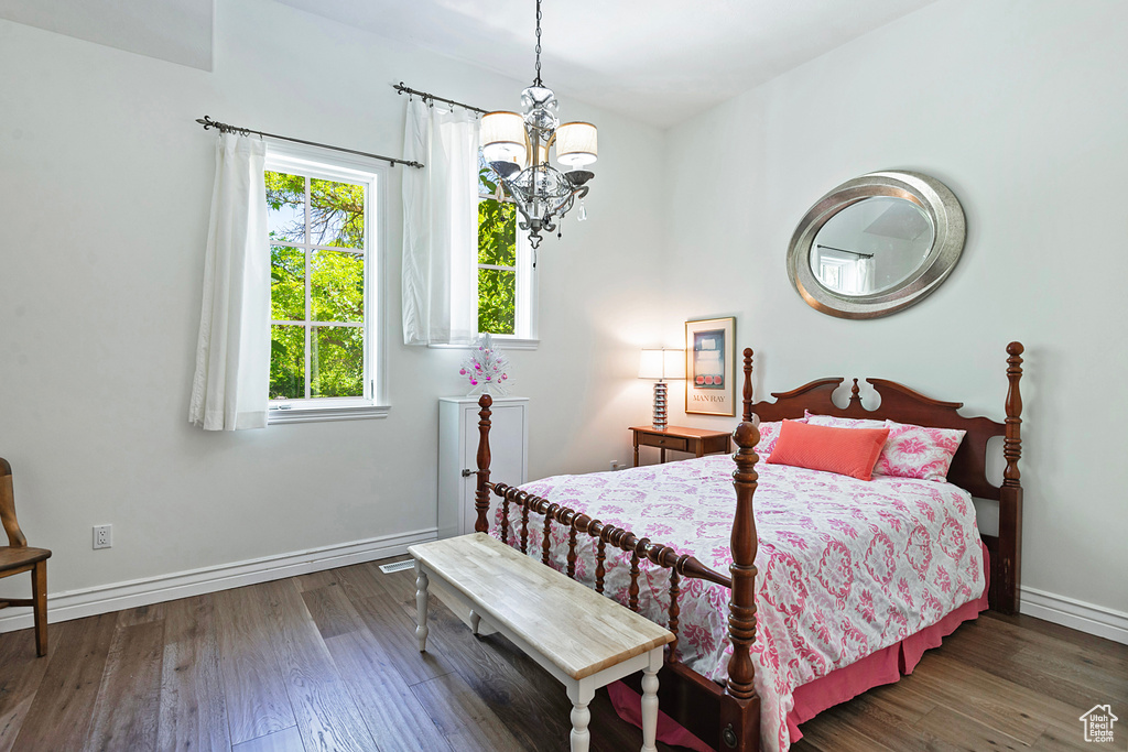 Bedroom with a chandelier, baseboards, and wood finished floors