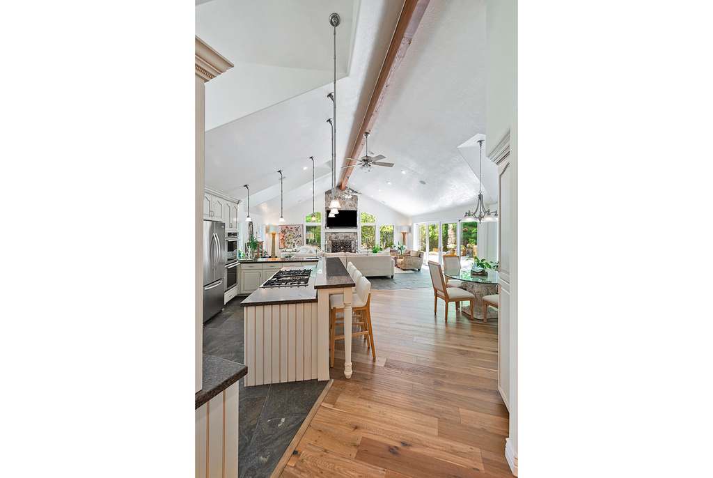 Kitchen with open floor plan, dark countertops, ceiling fan, beamed ceiling, and stainless steel appliances