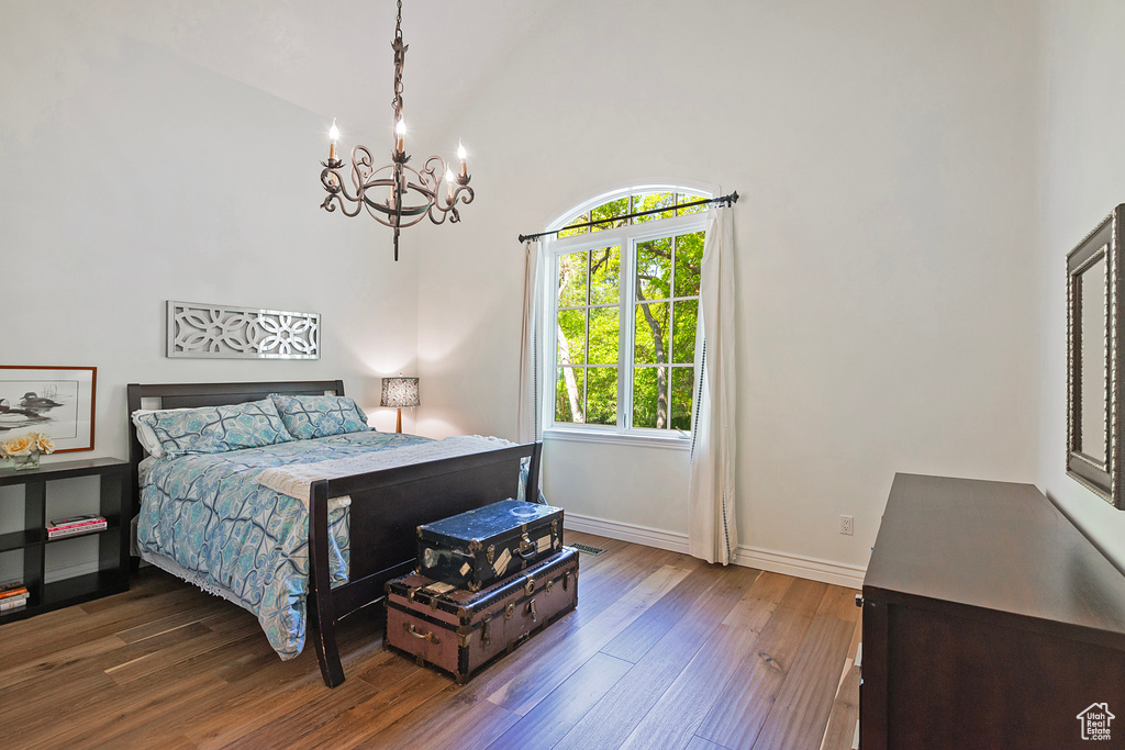 Bedroom with a chandelier, dark wood-style floors, and baseboards