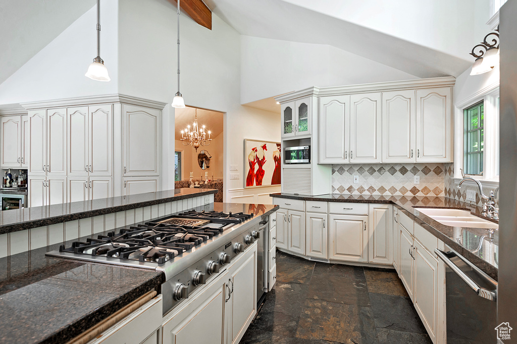Kitchen with high vaulted ceiling, a sink, stainless steel appliances, tasteful backsplash, and hanging light fixtures