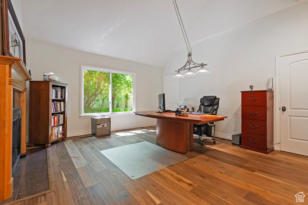 Office featuring hardwood / wood-style flooring, vaulted ceiling, baseboards, and a glass covered fireplace