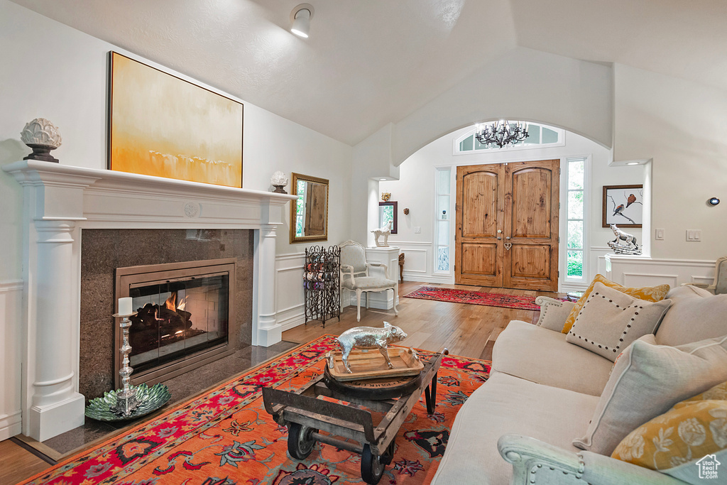 Living room featuring arched walkways, wood finished floors, a decorative wall, plenty of natural light, and vaulted ceiling